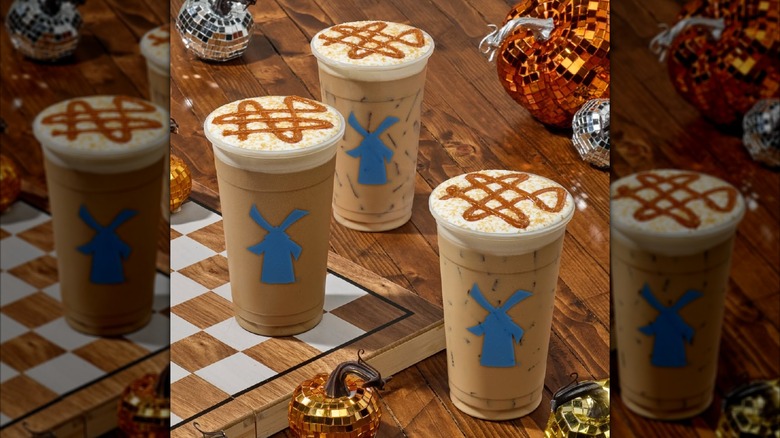 Three pumpkin caramel lattes from Dutch Bros on a wooden table with pumpkin decorations.