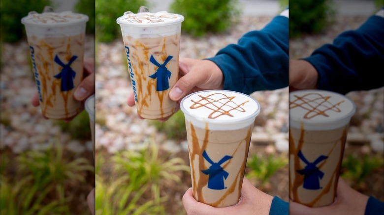 Person holding two iced cookie butter lattes from Dutch Bros in outdoor setting
