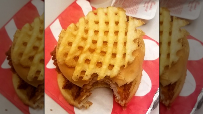 A big waffle fry sits on top of a Chick-fil-A sandwich.