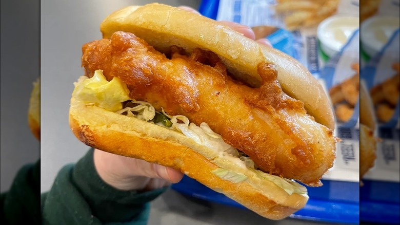 A hand holds a Culver's fried fish sandwich