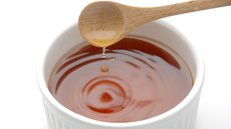 A wooden spoon pours malt vinegar into a ramekin
