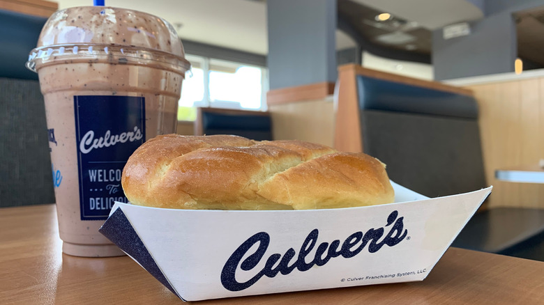 Culver's fish sandwich peeking out of its paper boat with a shake in the background