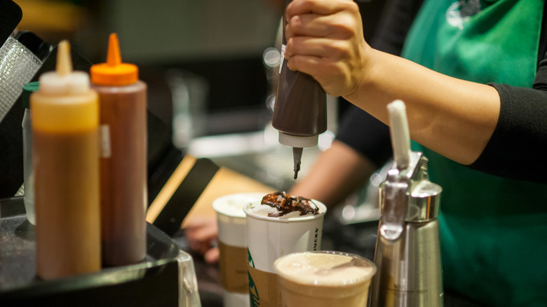A Starbucks barista squeezing Mocha Sauce on an espresso drink