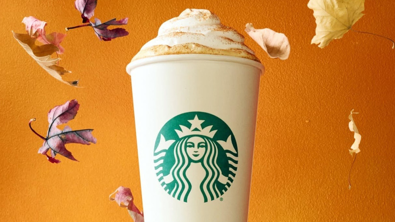 A Starbucks Pumpkin Spice Latte against a background of falling leaves