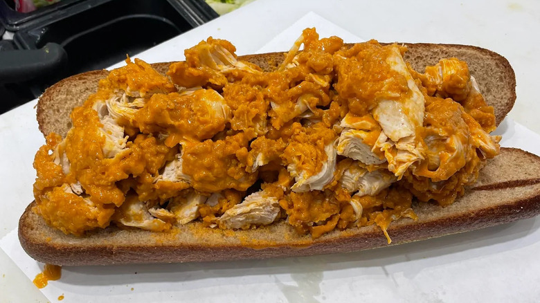 a sub roll overflowing with sauced, chopped chicken tenders