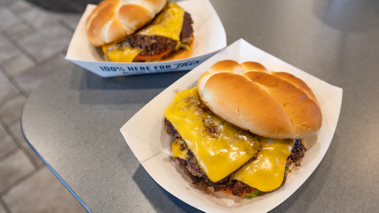 Two ButterBurgers with cheese from Culver's on top of gray table