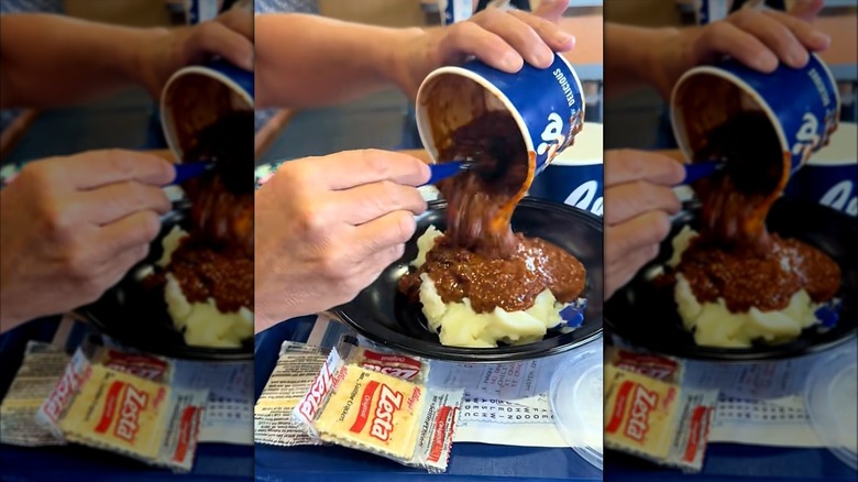 Customer pouring Culver's chili into black bowl of mashed potatoes with packet of crackers on the side