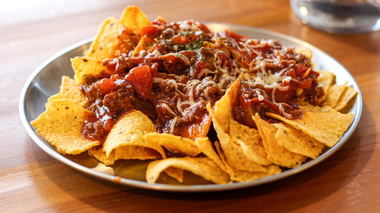 Plate of nachos with tortilla chips, chili, and shredded cheese