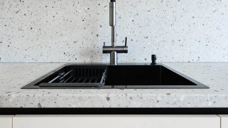 Sleek kitchen sink with a matte black faucet and a speckled white countertop