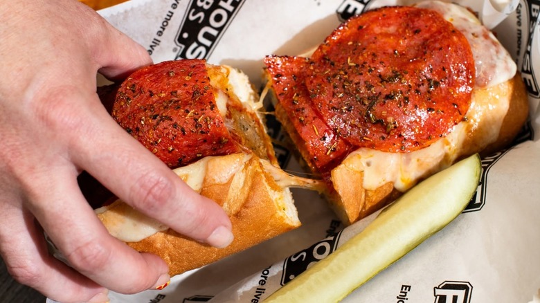 Hand reaching for a pepperoni meatball sub