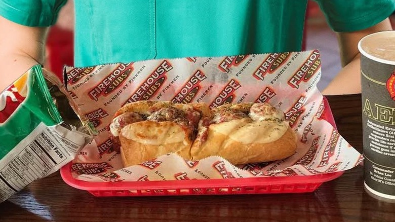 Meatball sub in red tray with drink and chips