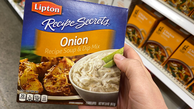 A hand holding Lipton onion soup mix at grocery store