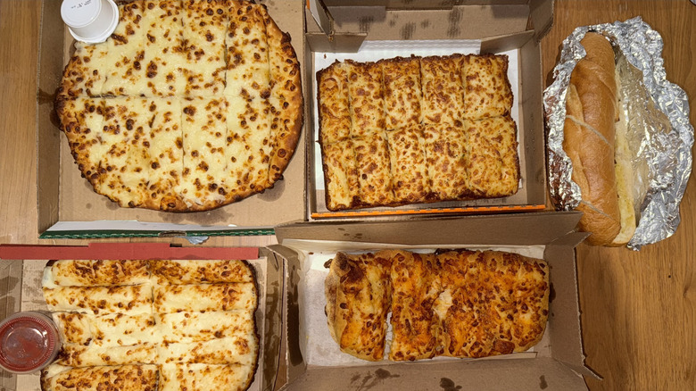 5 different closed cases of cheesy bread displayed on a wood surface.