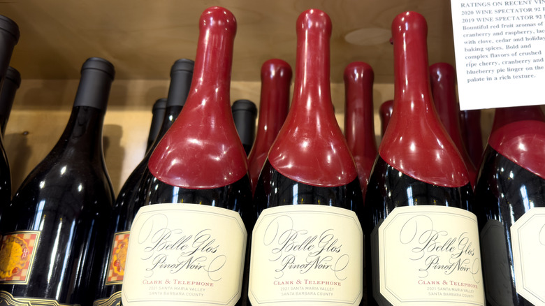 Red wax bottles of Belle Glos Pinot Noir stacked in a crate for retail sale