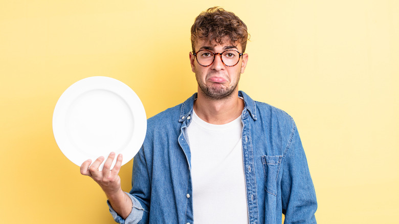 Sad person holding up an empty plate