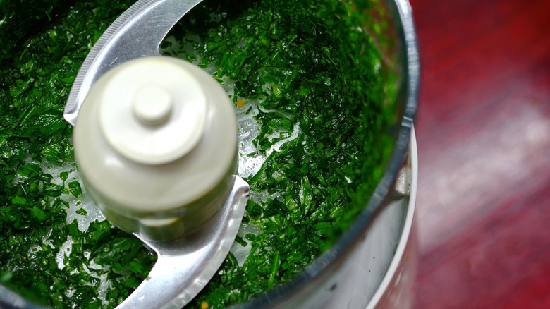 Blending basil leaves in a food processor.