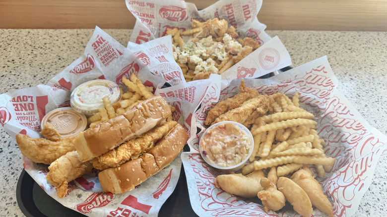 Side view of chicken sandwich, fries, and trays