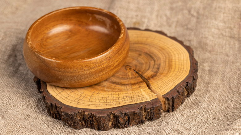 An acacia bowl placed on the edge of a round wood slab