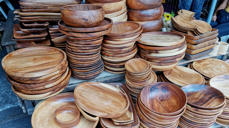 Acacia plates, bowls, and trays stacked to sell at a market