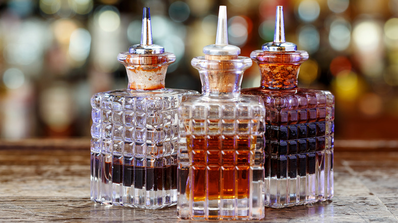 Three decorative decanters of bitters sit on a bar