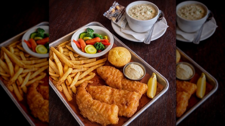North and South Seafood & Smokehouse fish and chips on metal tray with corn muffin and vegetables next to bowl of clam chower