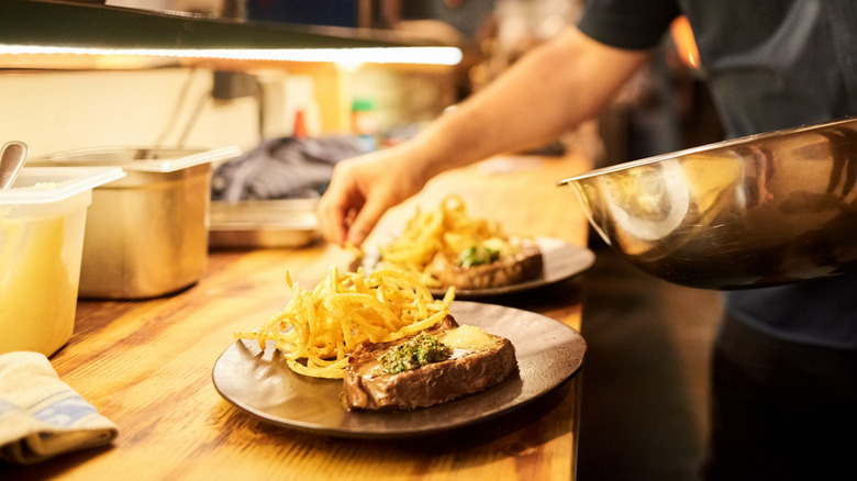 Restaurant chef preparing steak dish