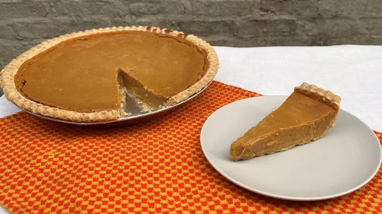 A Costco pumpkin pie next to a slice on a plate.