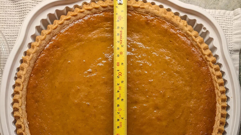 A measuring tape in the middle of a Costco pumpkin pie.