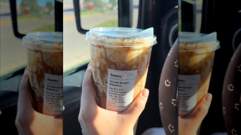A woman holding up an iced Starbucks sugar cookie espresso drink