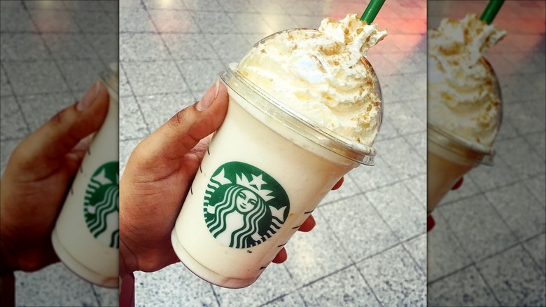 A woman holding a Starbucks Snowball frappuccino with whipped cream and sprinkles