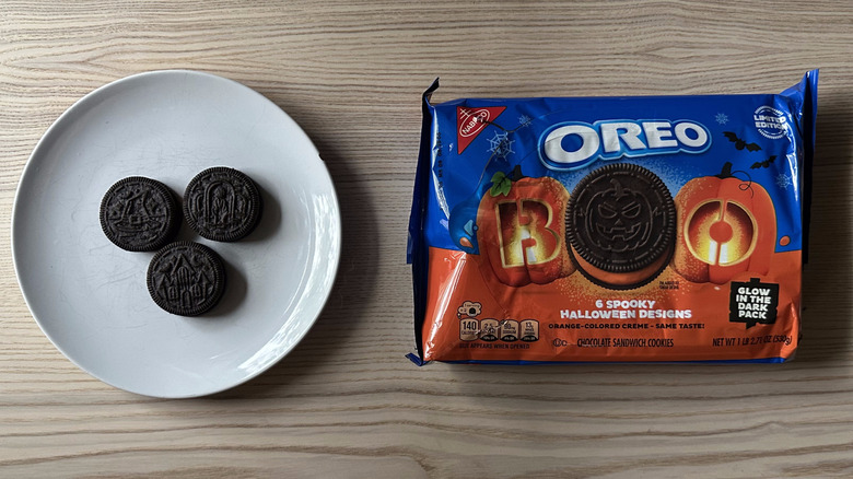 Package of Halloween Oreos on wooden table with three pieces on plate