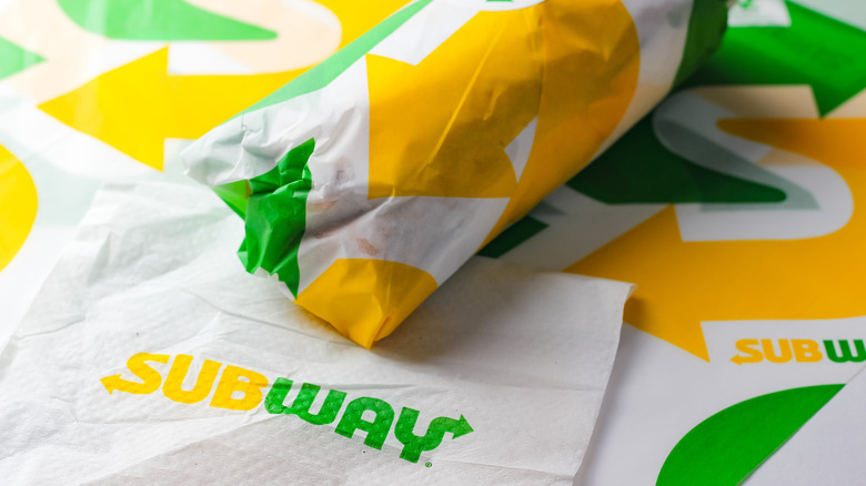Wrapped Subway sandwich beside napkin with logo on it