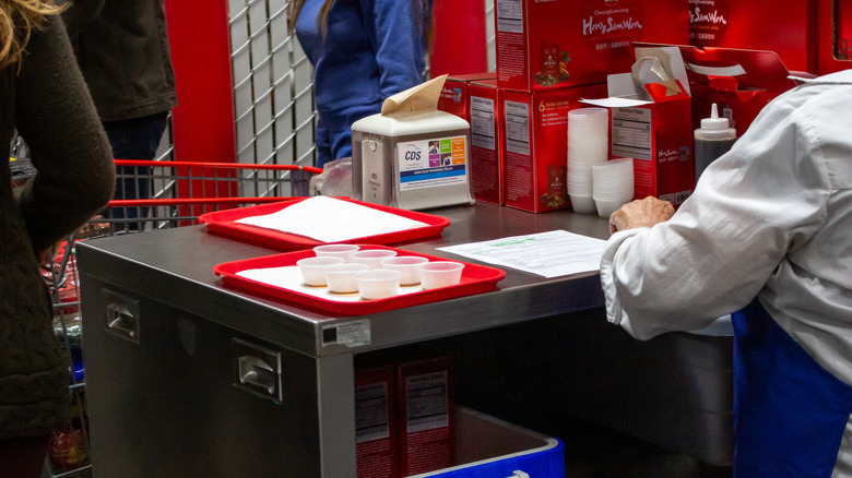a Costco free sample station with one empty tray and one tray filled with samples in small plastic cups
