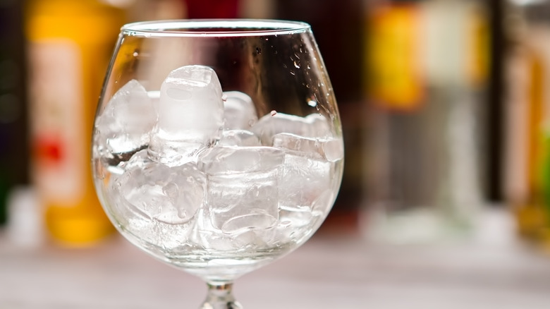 A goblet glass of melting ice cubes