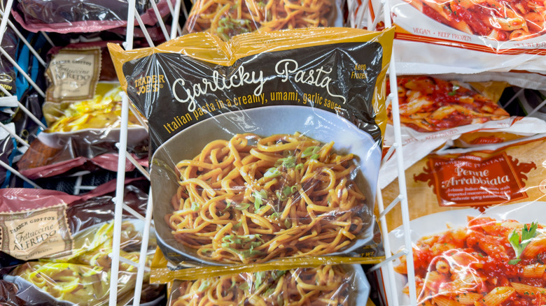 Close up of garlicky pasta in packaging above freezer compartments of Trader Joe's