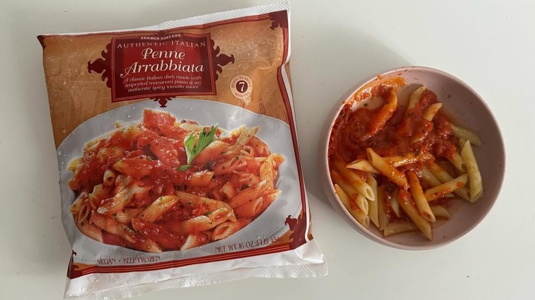 Bowl of freshly prepared penne arrabbiata alongside package