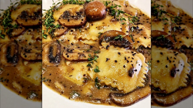 Close up image of ravioli swimming in mushroom sauce alongside mushroom slices