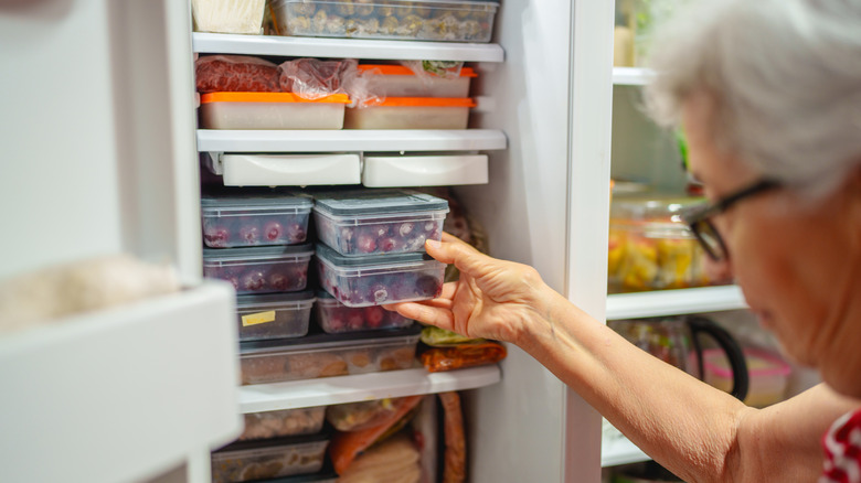 A person pulls out a container of frozen food from the freezer