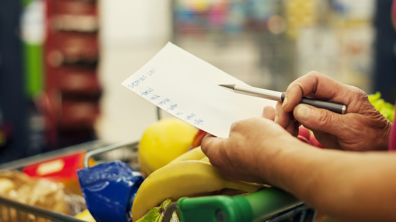A person checks their shopping list at the grocery store
