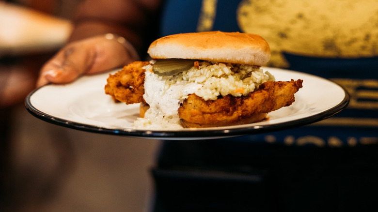 Waiter holding the sweet tea fried chicken sandwich