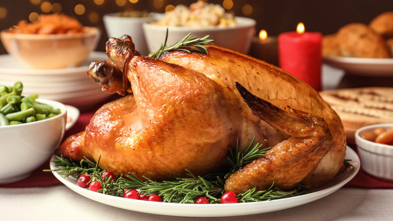Thanksgiving turkey on table surrounded by side dishes and festive decorations