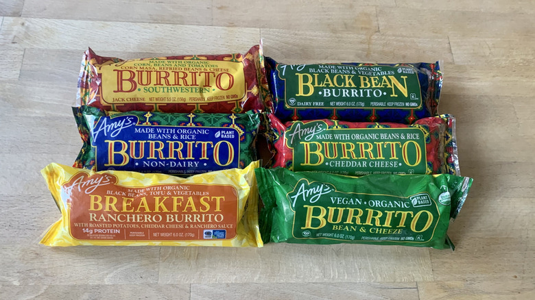 six frozen Amy's burritos in wrappers on wood background