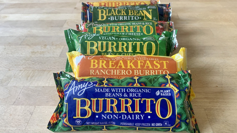 six frozen Amy's burritos in wrappers on wood background