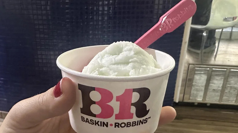 A person holding a scoop of Baskin Robbins daiquiri ice scoop in a cup
