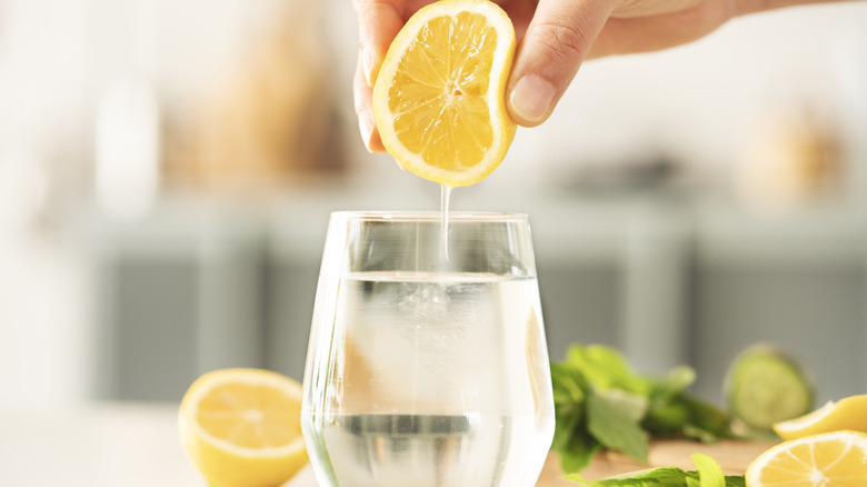 Hand squeezing lemon into drinking water