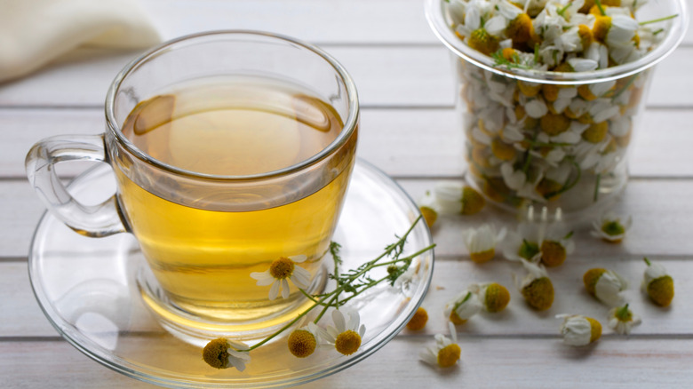 A jar of chamomile flowers and a cup of chamomile tea