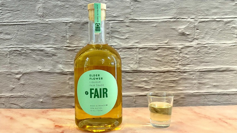 Shot glass of Fair Elderflower liqueur on table next to bottle