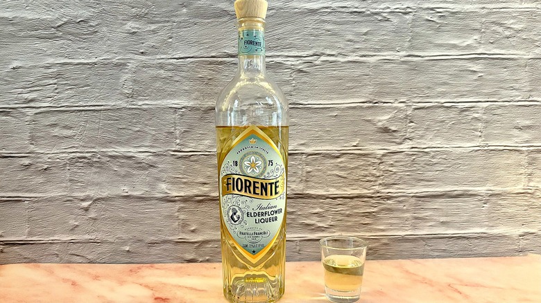 Shot glass of Fiorente Elderflower liqueur on table next to bottle