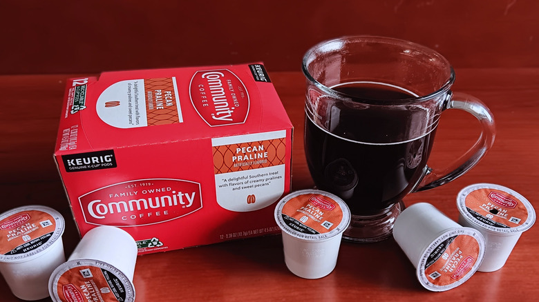 Box of Community Pecan Praline flavored coffee with mug of black coffee.