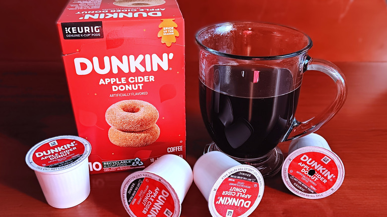 Box of Dunkin' Apple Cider Donut flavored coffee K-cups with mug of black coffee